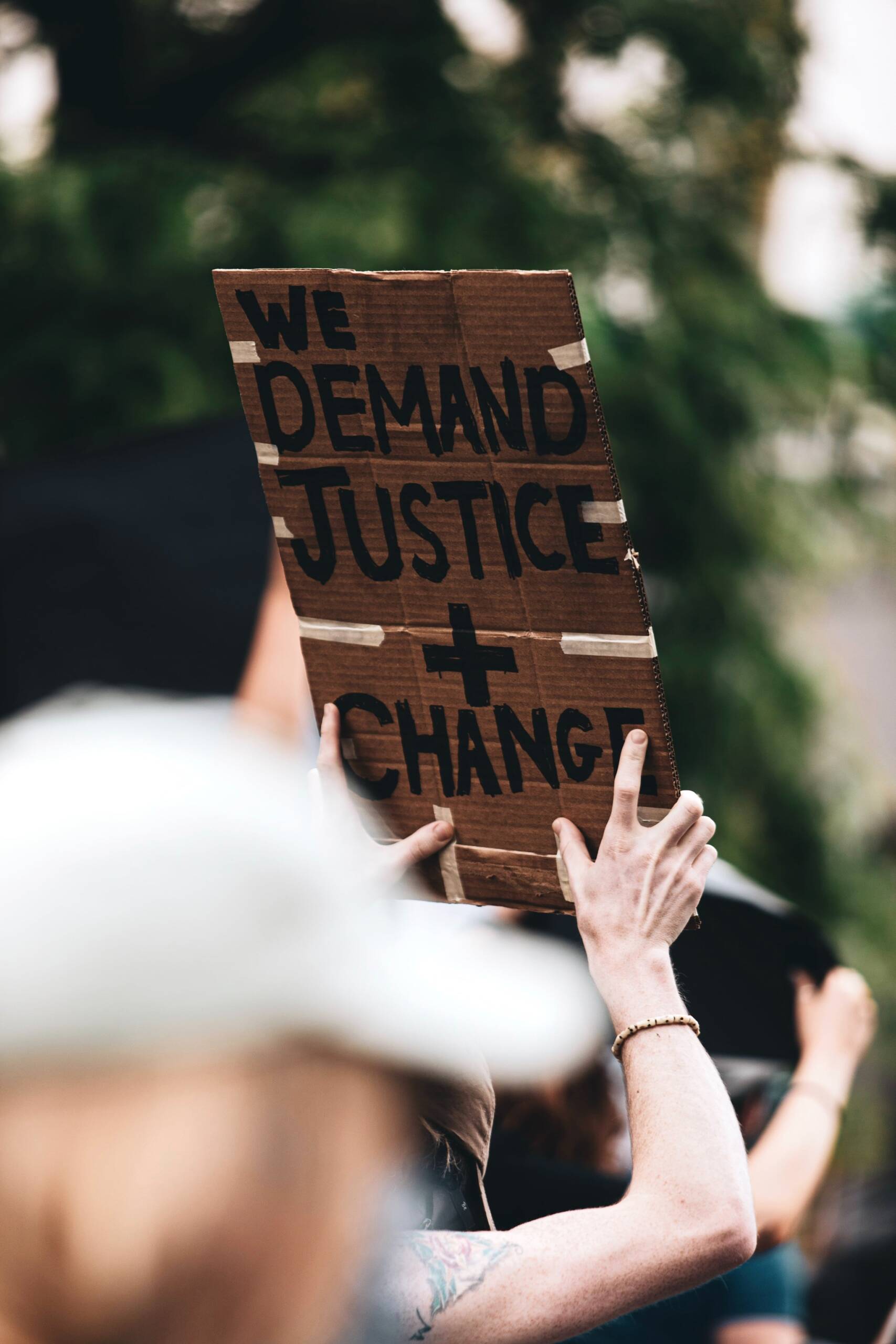 Foto einer Hand, die ein Plakat hält mit der Aufschrift "We demand justice and change"