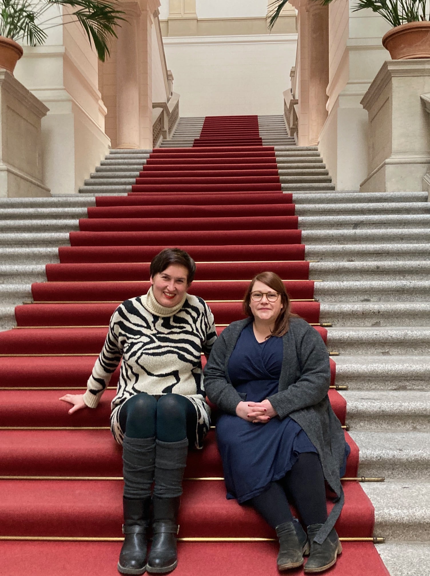 Dagmar Lettner und Sarah Wendler sitzen auf einer Treppe im Abgeoprdnetenhaus